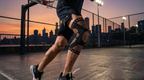 Genouillère de compression noire et cuivre portée au basket, sur un terrain extérieur au crépuscule