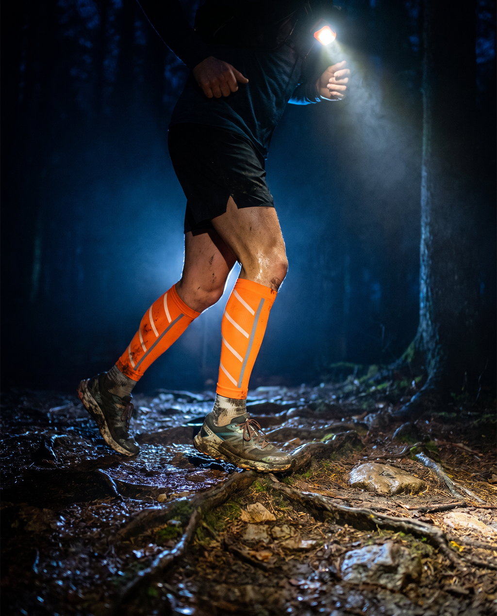 Manchons de compression orange pour mollets portés en trail de nuit, à la lampe frontale