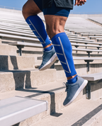 Manchons de compression bleus pour mollets portés pendant une séance dans les escaliers d'un stade